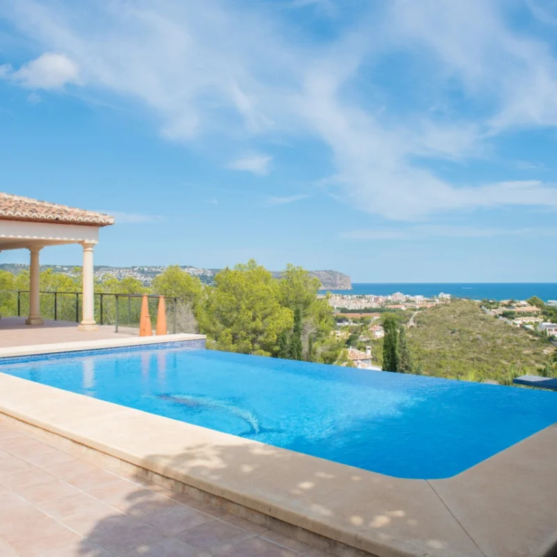 Infinity zwembad met een betegeld terras en een klassieke veranda met zuilen. Biedt panoramisch uitzicht op de Middellandse Zee en de kust van Jávea.