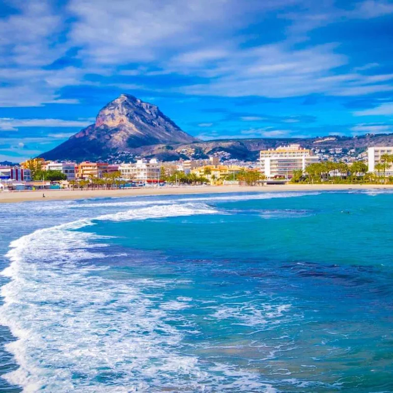 Panoramisch uitzicht op het strand van Jávea met de Montgó-berg op de achtergrond. Residentiële gebouwen langs de kust.