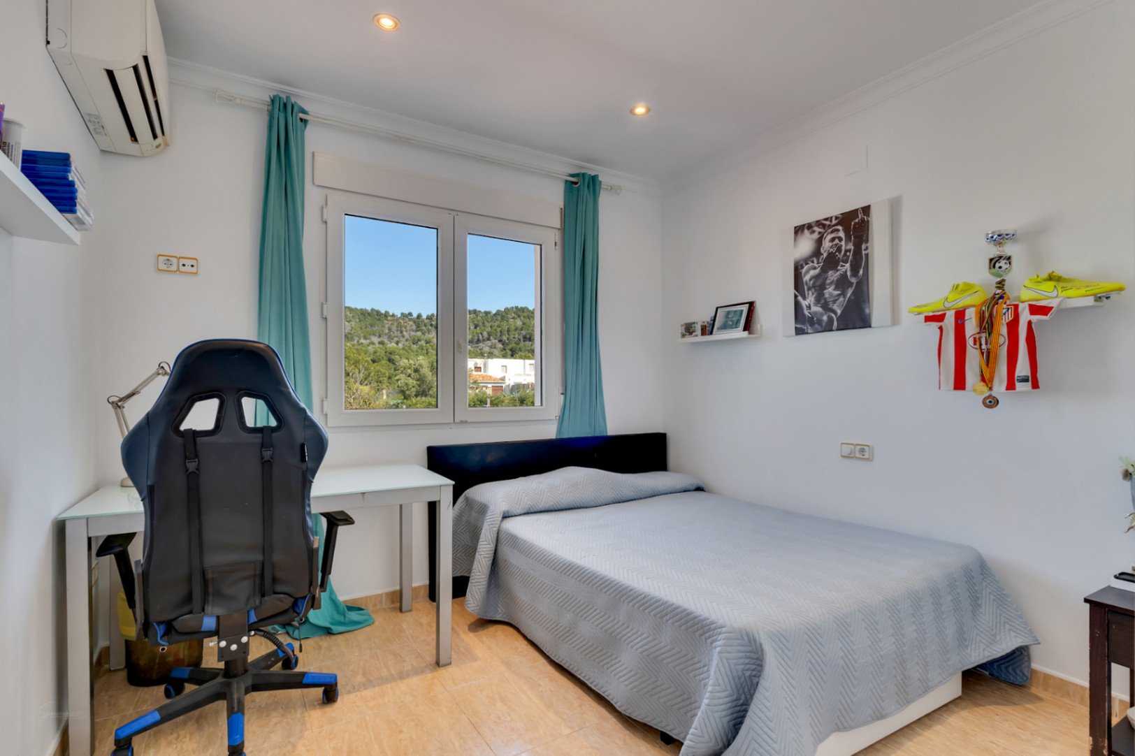 Lichte slaapkamer met een werkplek, voorzien van airconditioning en een PVC-raam met vrij uitzicht op de omliggende natuur en heuvels.