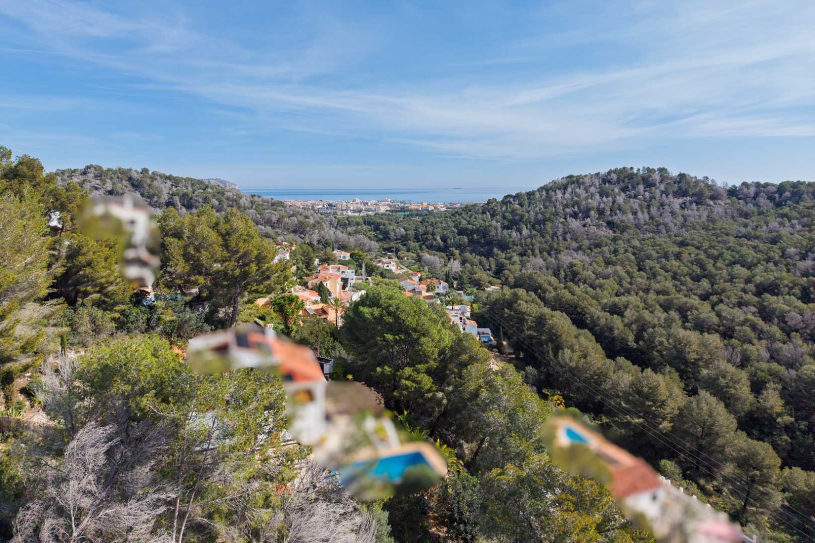 Panoramisch uitzicht vanaf het perceel over de met pijnbomen begroeide heuvels naar de Middellandse Zee en de kustplaats Jávea.