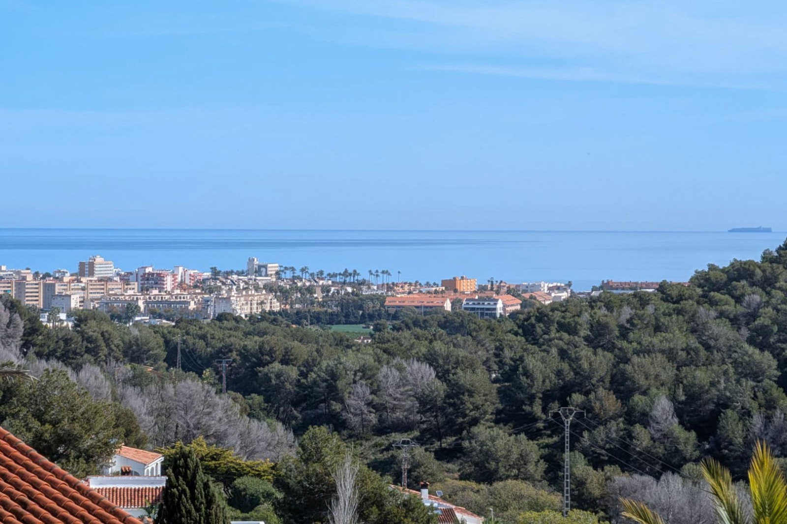Verhoogd panoramisch uitzicht vanaf het perceel over de Middellandse Zee, de kustlijn van Jávea en de omliggende beboste heuvels.