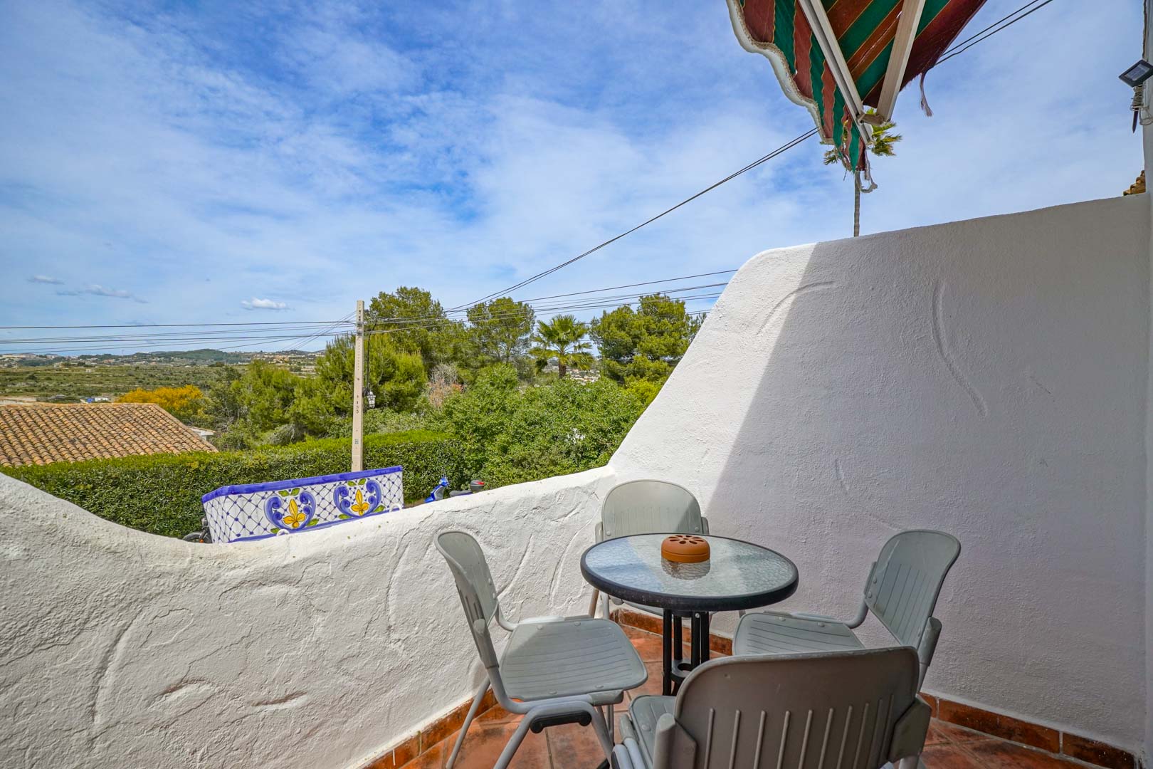 Buitenterras met terracotta tegels en een zitgedeelte, met vrij uitzicht over de vallei en het omliggende groen van Moraira.