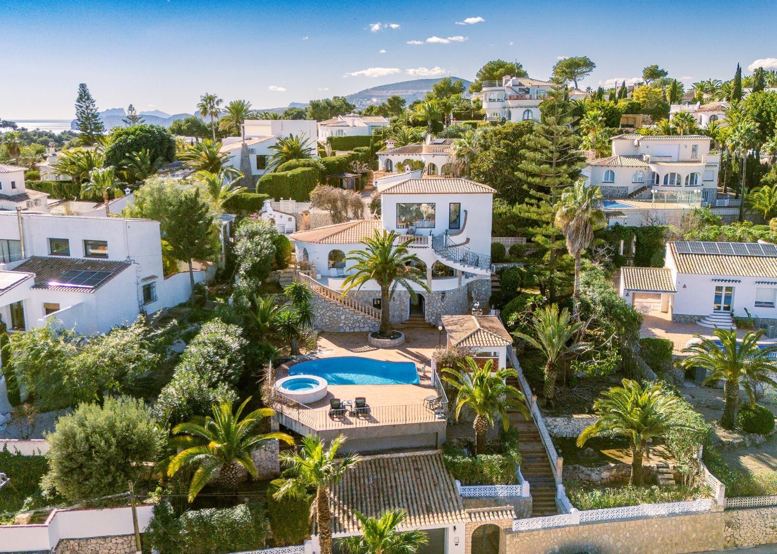 Luchtfoto van de villa met meerdere niveaus, privézwembad, ronde jacuzzi en zonneterrassen, omgeven door een volgroeide mediterrane tuin in Balcón al Mar.