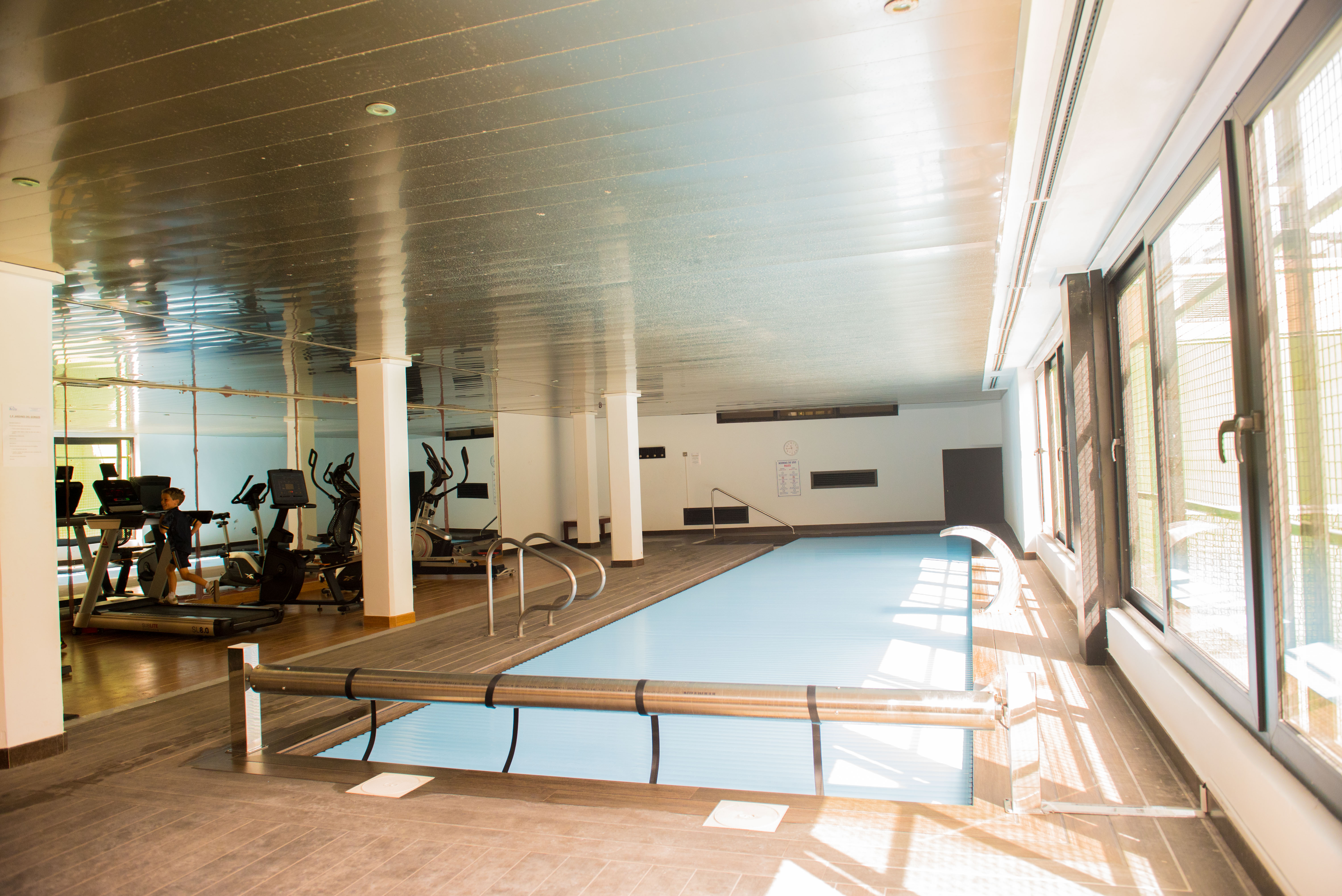 Binnenzwembad met verwarmd water en afdekking, gecombineerd met een fitnessruimte voorzien van loopbanden en hometrainers.