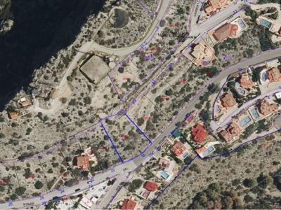 Luchtfoto van het stedelijke perceel, blauw omrand, gelegen aan de 'ROMER' weg in de urbanisatie Monte Pedreguer. Het onbebouwde terrein is zichtbaar, omringd door bestaande woonhuizen.