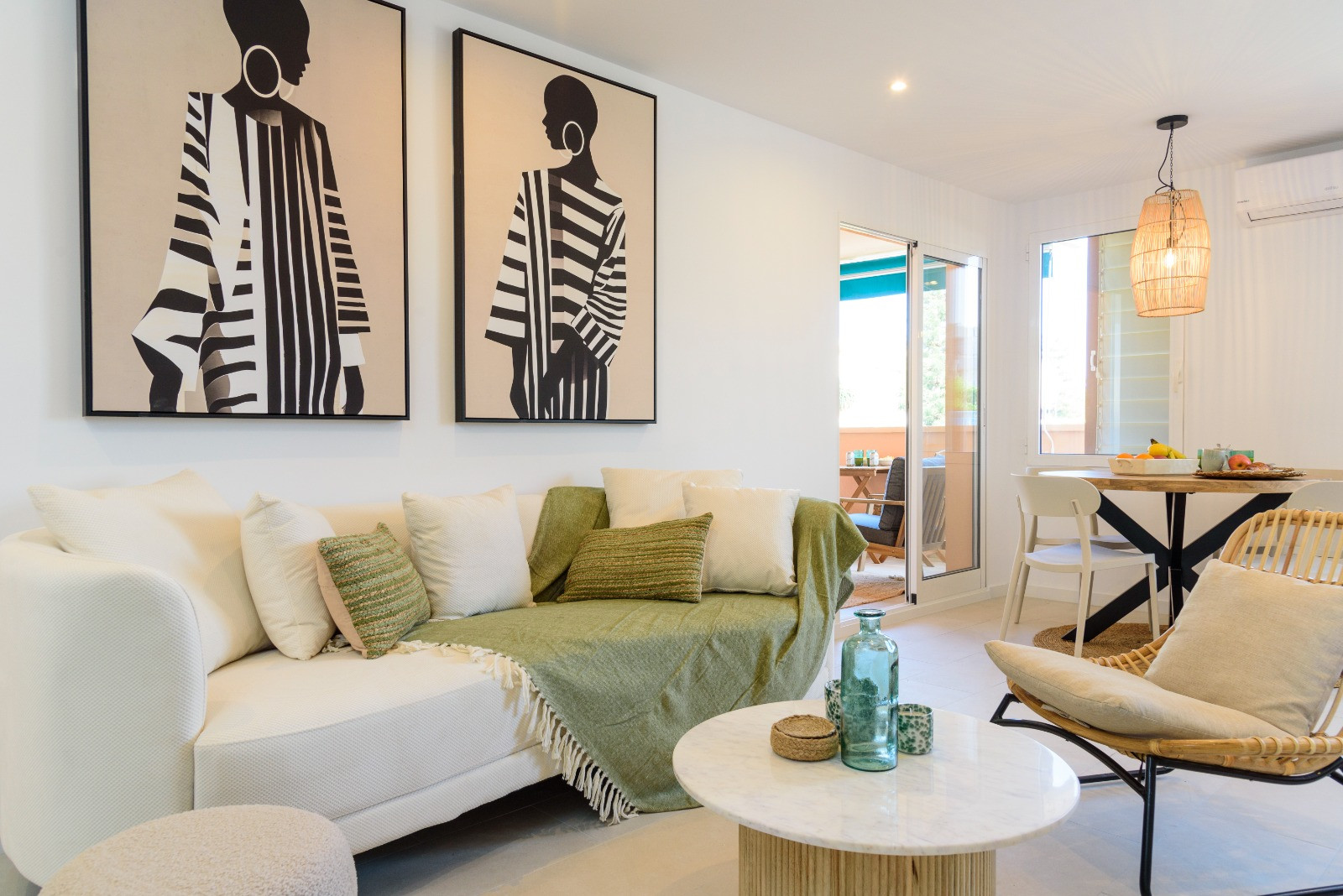 Eigentijdse woonkamer met grote kunstwerken, een marmeren salontafel en directe toegang tot het terras via glazen deuren.