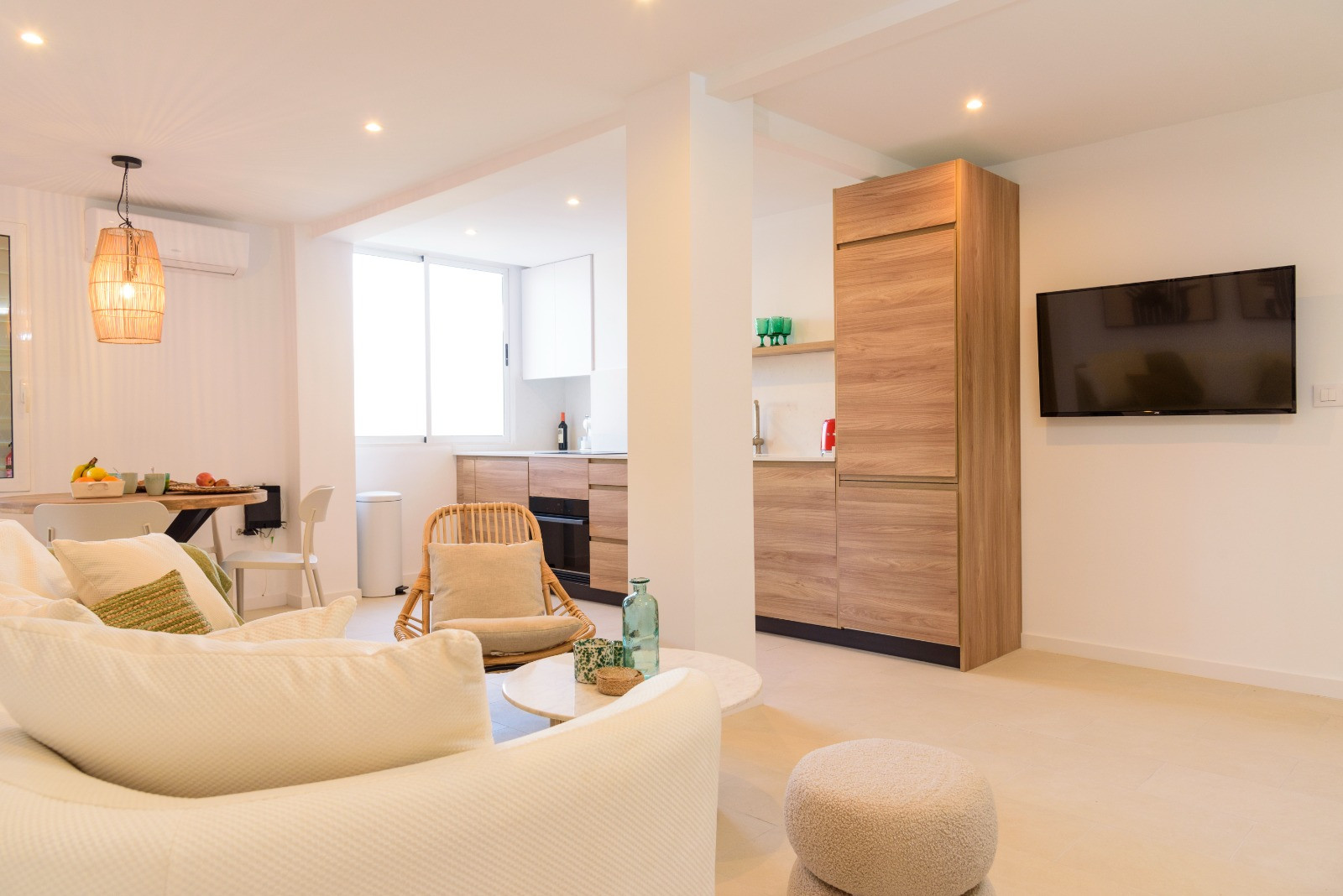 Open woonruimte met een moderne keuken in houtlook, een lichte zithoek met neutrale meubels en een marmeren salontafel onder subtiele inbouwspots.
