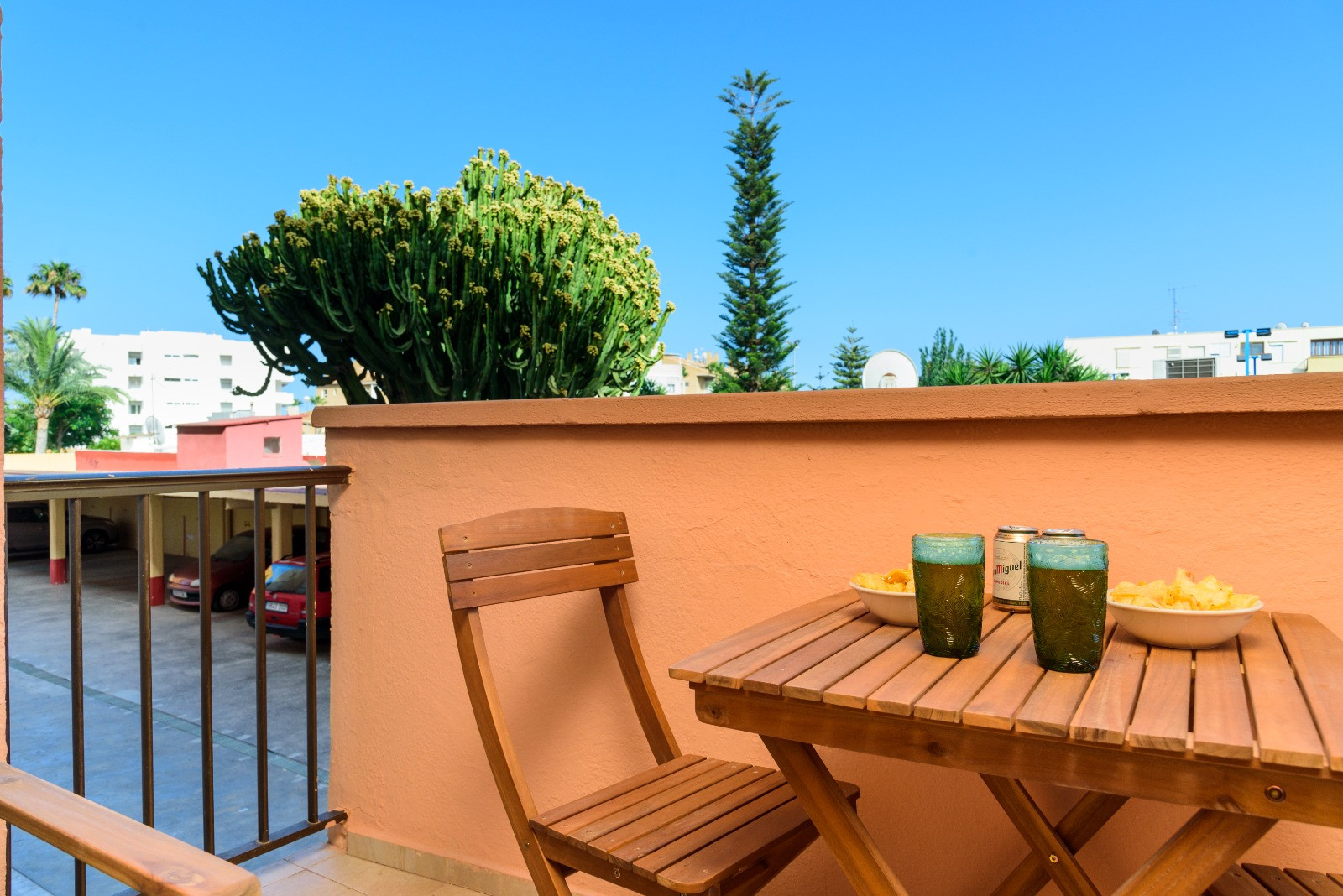 Privéterras met houten meubilair, ideaal voor hapjes in de buitenlucht. Het biedt uitzicht op tuinen met cactussen en palmbomen onder een helderblauwe hemel.
