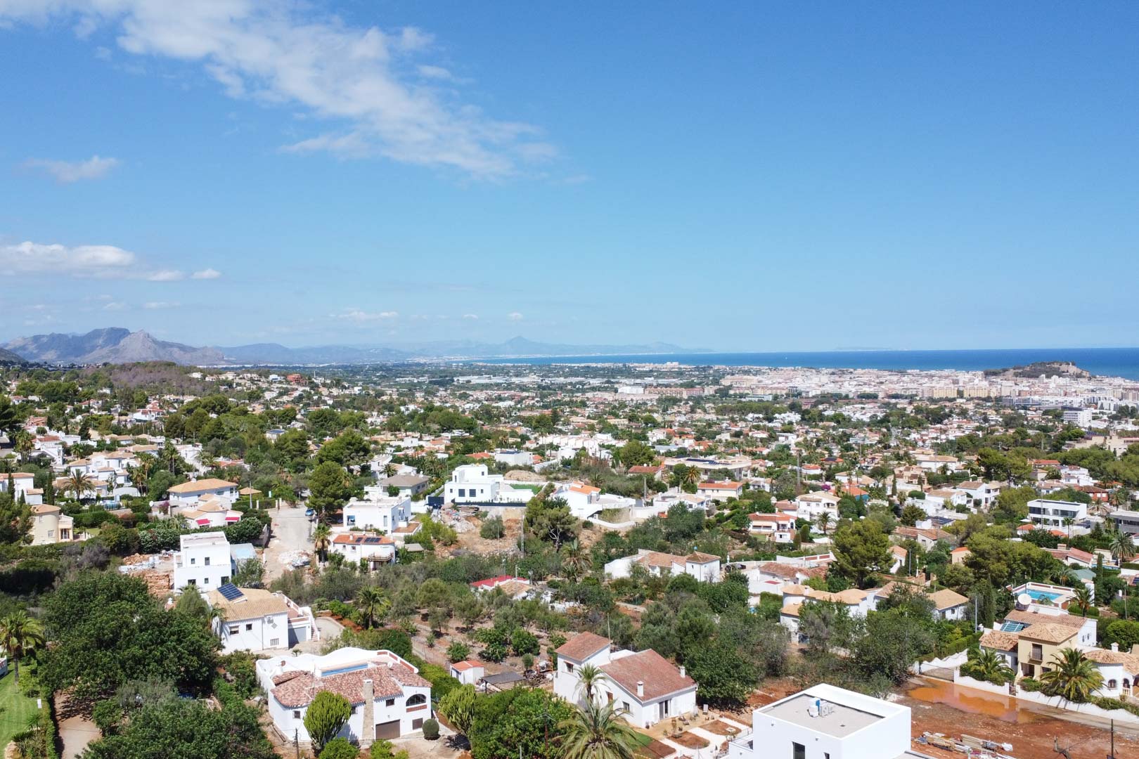 Panoramisch luchtfoto van de residentiële wijk in Dénia, met een weids uitzicht over de Middellandse Zee en de omliggende kustlijn.