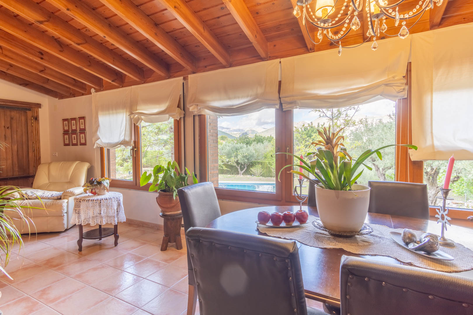 Lichte eetkamer met plafonds van Fins vurenhout, terracotta vloeren en grote ramen met direct uitzicht op het zwembad en de omliggende natuur van Alicante.