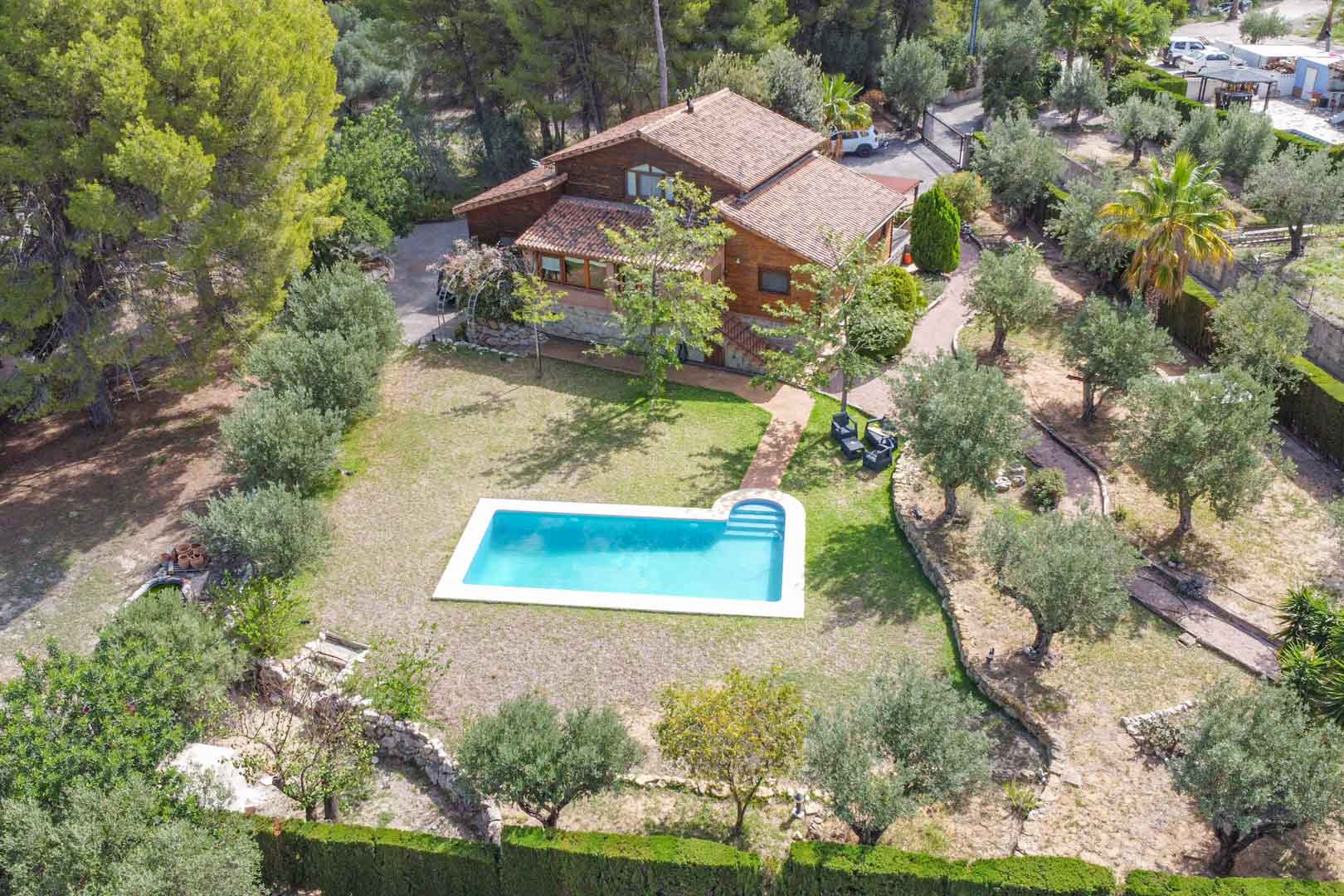 Luchtfoto van de villa van Fins grenenhout en natuursteen, met het privézwembad omgeven door olijfbomen en mediterrane tuinen in Orba.