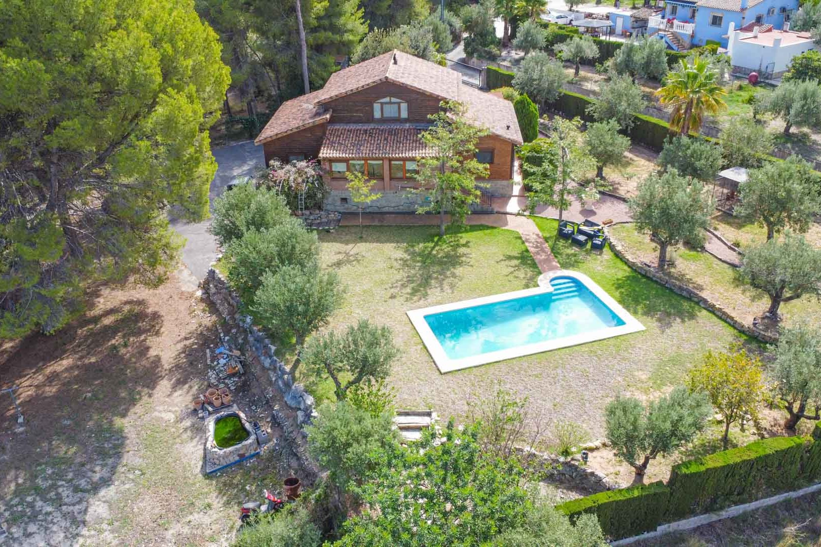Luchtfoto van de villa van Fins vurenhout met privézwembad, omgeven door mediterrane tuinen met olijfbomen en pijnbomen in Orba.