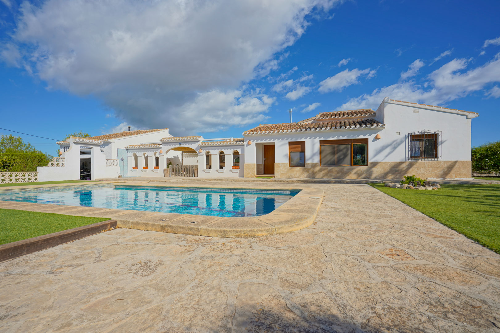 Buitenaanzicht van de villa met privézwembad, omgeven door een ruim natuurstenen terras en verzorgde gazons in mediterrane stijl.