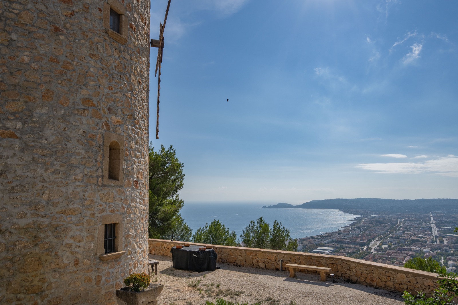 Panoramisch uitzicht vanaf de stenen toren over de baai van Jávea en de Middellandse Zee, met een grindterras en een natuurstenen ommuring.