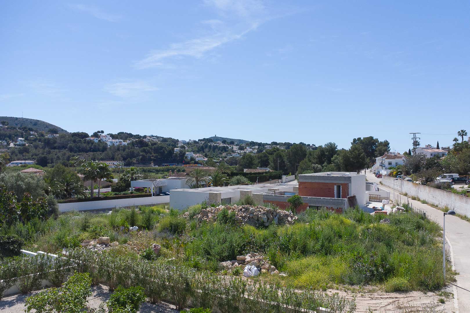 Buitenaanzicht van de villa in aanbouw, met de moderne structurele vormgeving en de integratie in het mediterrane heuvellandschap van Moraira.
