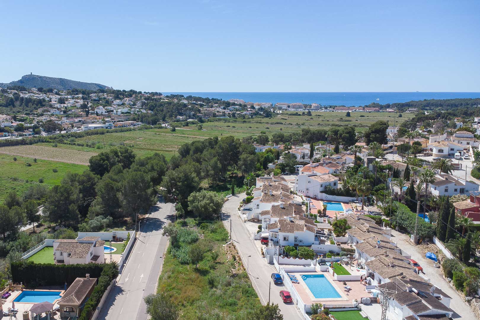 Panoramisch luchtaanzicht van Moraira met uitzicht op de Middellandse Zee, omgeven door groene zones en de residentiële villawijk van de Costa Blanca.