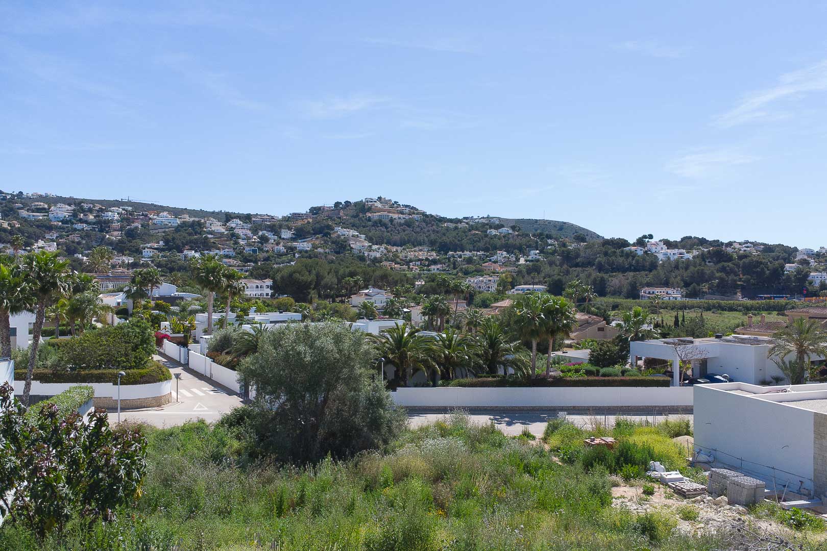Panoramisch uitzicht vanaf het pand op het woonlandschap van Moraira, met groene heuvels en mediterrane architectuur onder een heldere hemel.