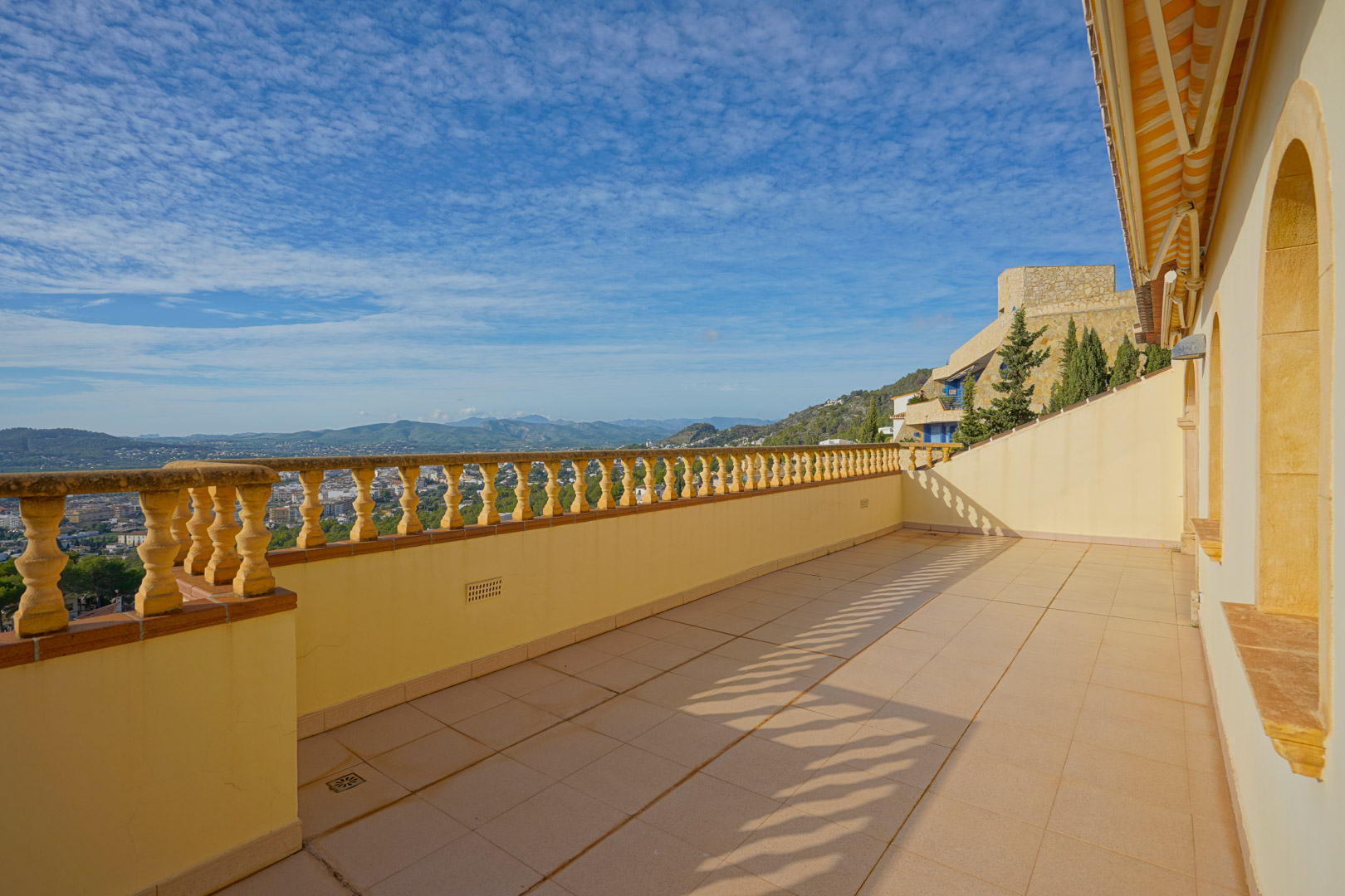 Bovenste terras met een traditionele balustrade en tegelvloer, met een weids panoramisch uitzicht over de vallei van Jávea en de omliggende bergen.