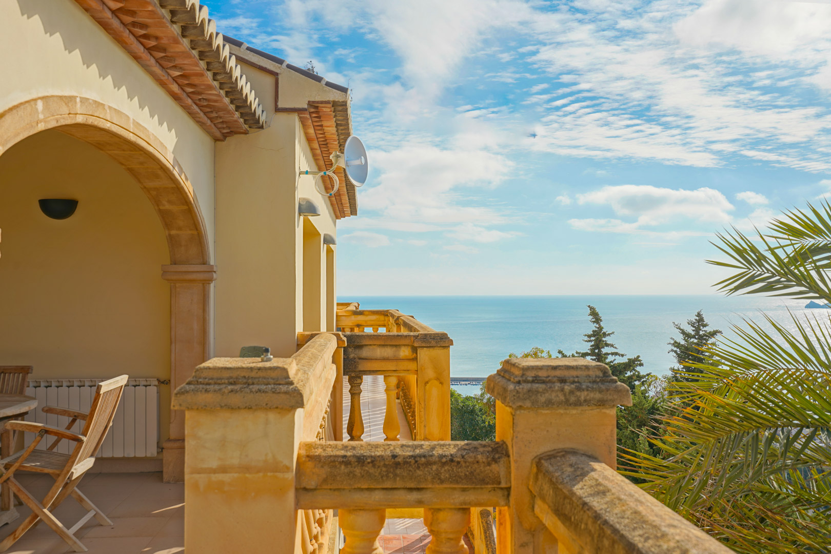 Bovenste terras met stenen balustrades en traditionele bogen, met een panoramisch uitzicht over de Middellandse Zee en de kustlijn van Jávea.