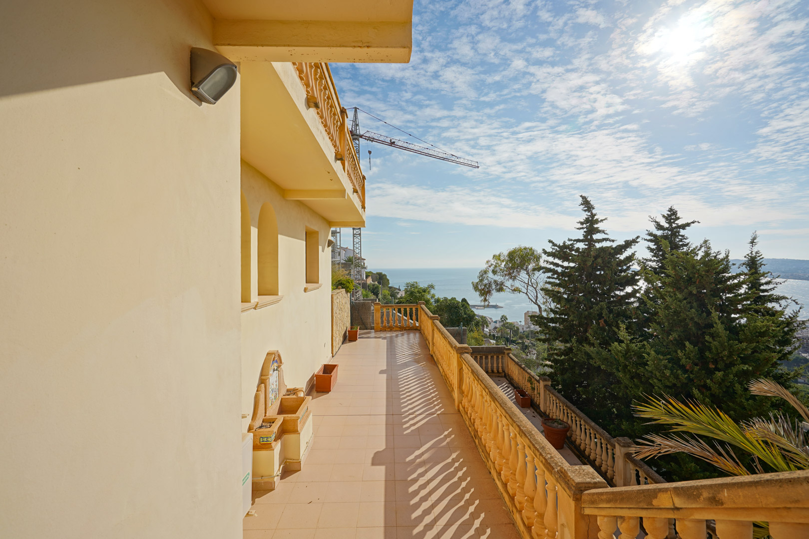 Langgerekt terras met traditionele balustrades, een decoratieve wandfontein en weids uitzicht over de Middellandse Zee en de kust van Jávea.
