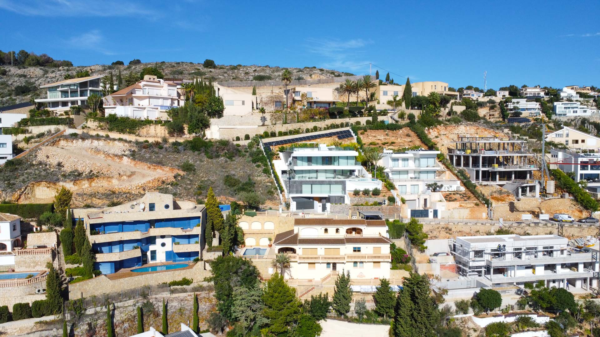 Luchtfoto van de villa op de helling van La Corona, met de traditionele architectuur van drie verdiepingen, pannendaken en terrassen die opgaan in het mediterrane landschap.