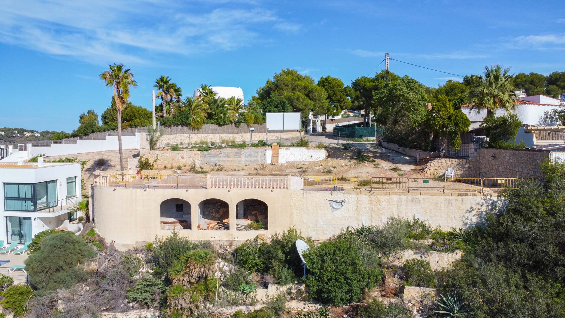Verhoogd bouwperceel met bestaande boogstructuur, stenen steunmuren en mediterrane begroeiing, klaar voor de ontwikkeling van een luxe villa.