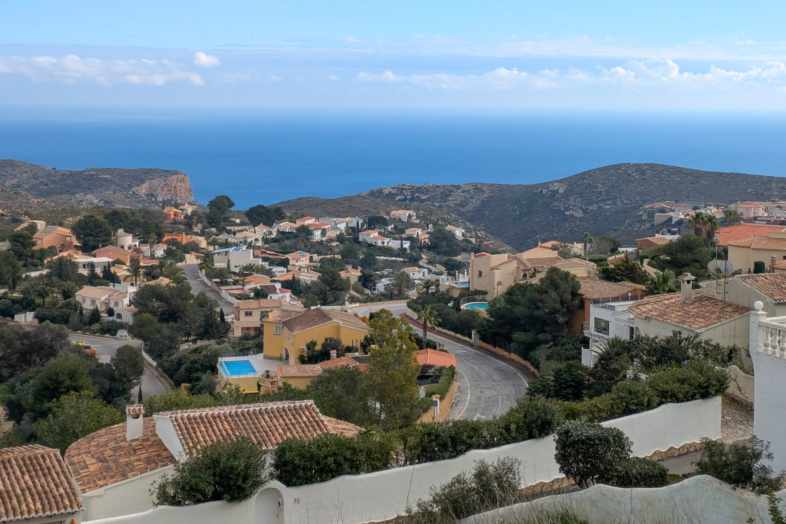 Panoramisch uitzicht vanuit Cumbre del Sol over de Middellandse Zee, met de gevestigde woonwijk en de ruige kustlijn van de Costa Blanca.