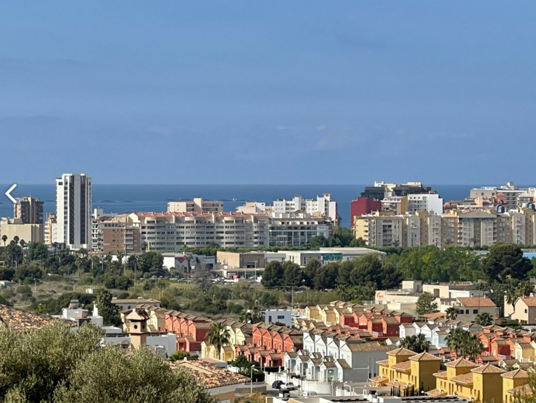 Panoramisch uitzicht vanaf het perceel over het stedelijke landschap van Calpe, met een mix van residentiële architectuur en de Middellandse Zee aan de horizon.