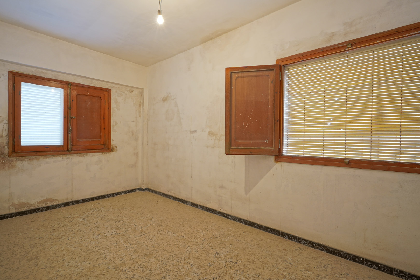 Te renoveren slaapkamer met originele terrazzo vloer, houten kozijnen met luiken en wanden die naar eigen smaak kunnen worden afgewerkt.