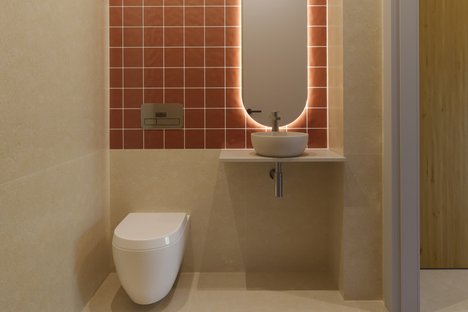 Modern gastentoilet met terracotta wandtegels, een hangend toilet en een ovale spiegel met indirecte verlichting boven een minimalistische wastafel.