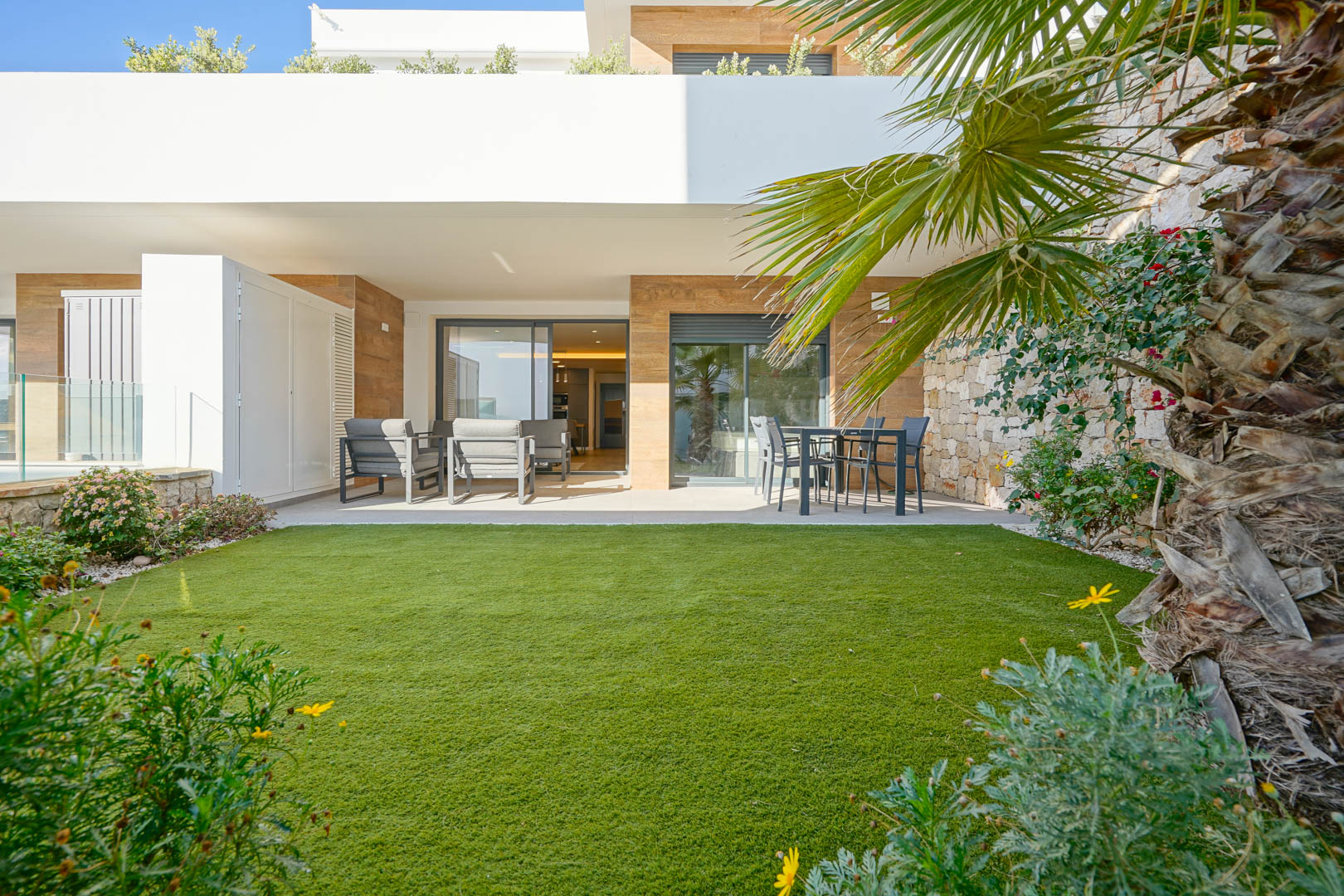 Overdekt terras van 23 m2 en een privétuin van 36 m2 met kunstgras, omgeven door een natuurstenen muur en met directe toegang tot de woonruimtes.