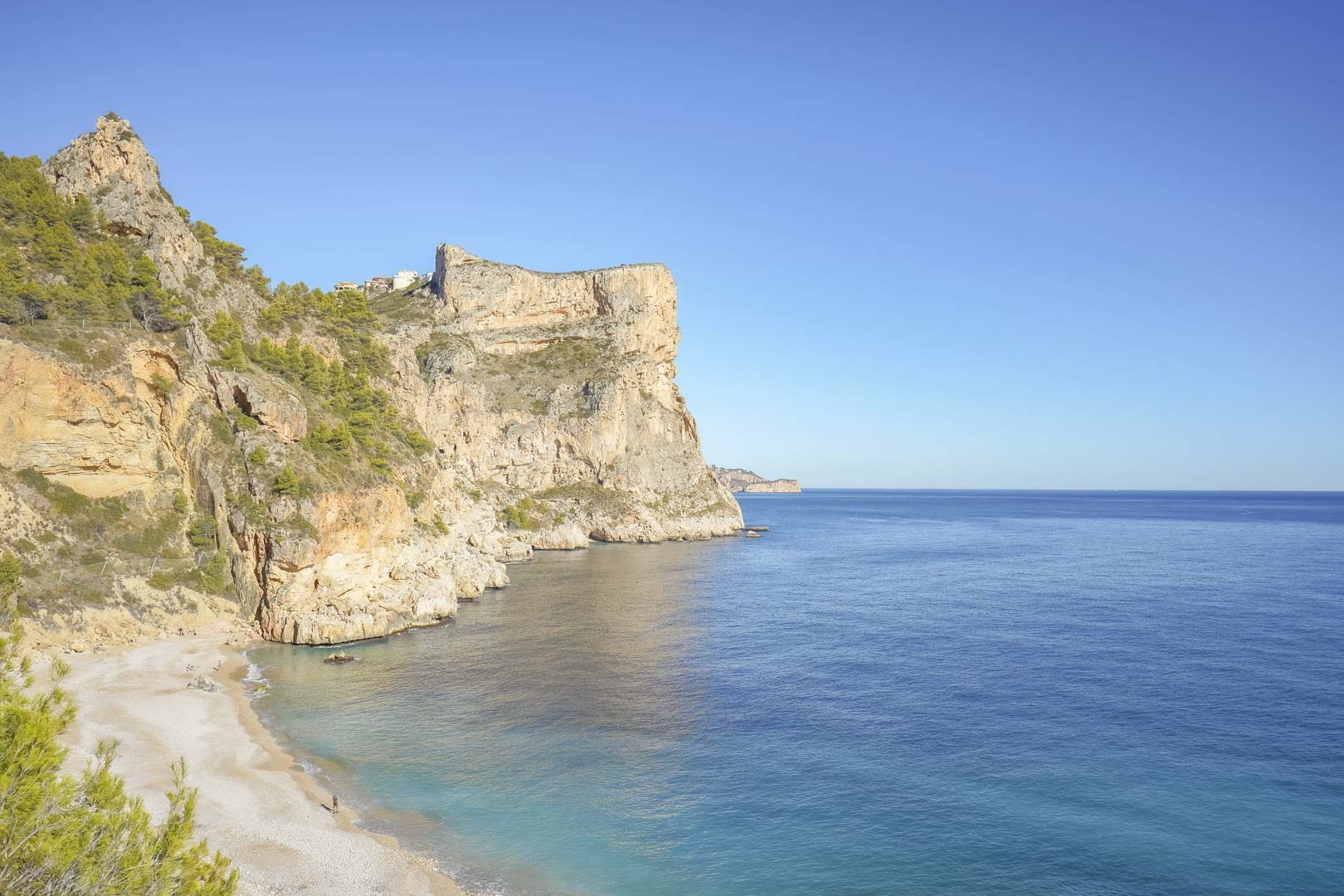 Panoramisch uitzicht op de idyllische Cala Llebeig met kalkstenen kliffen en kristalhelder water, te voet bereikbaar vanuit Monte Cala Gardens.