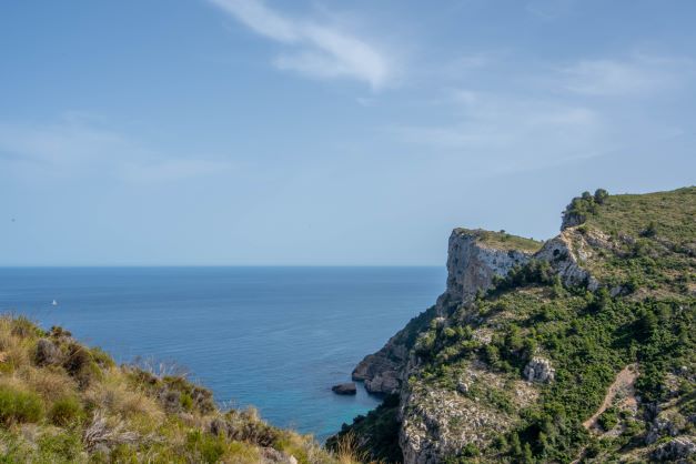 Panoramisch uitzicht op de mediterrane kustkliffen en de blauwe zee vanuit de natuurlijke omgeving van Cumbre del Sol.