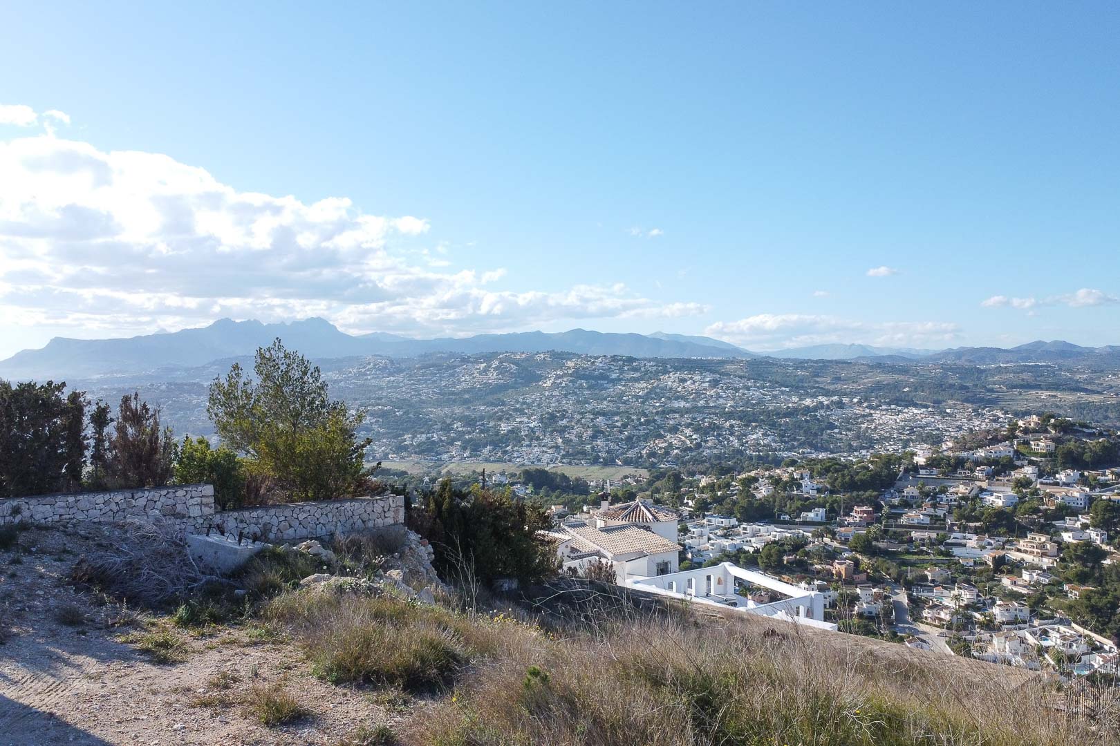 Panoramisch uitzicht op Moraira vanaf een heuvel, met uitzicht op het stadsbeeld en de bergen in de verte.