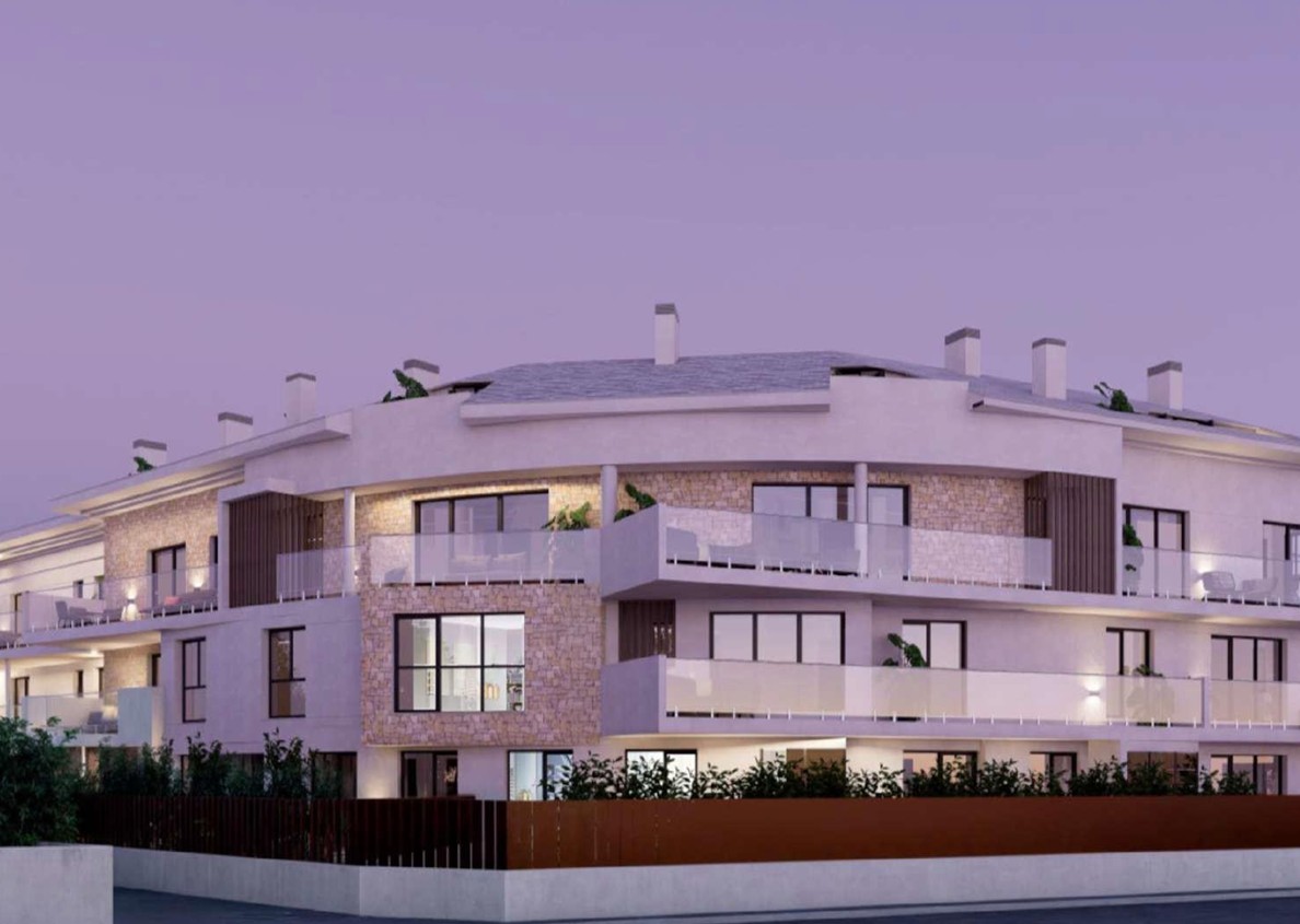Buitengevel van het residentiële complex in Javea, met natuurstenen details, ruime terrassen met glazen balustrades en geïntegreerde verlichting bij schemering.