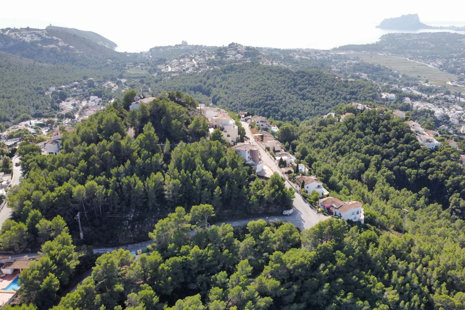 Luchtfoto van de woonwijk Paichi in Moraira, met de verhoogde ligging in een bosrijke omgeving en uitzicht op de Middellandse Zee en de Peñón de Ifach.