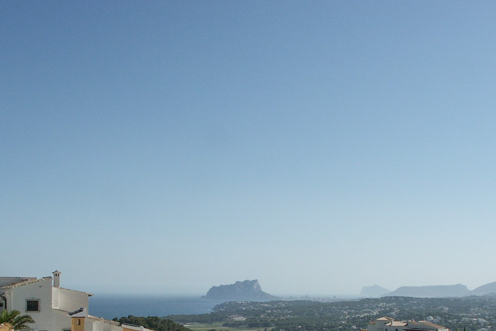 Panoramisch uitzicht vanaf het hooggelegen perceel op de kustlijn van Calpe, met het silhouet van de Peñón de Ifach aan de Middellandse Zee.