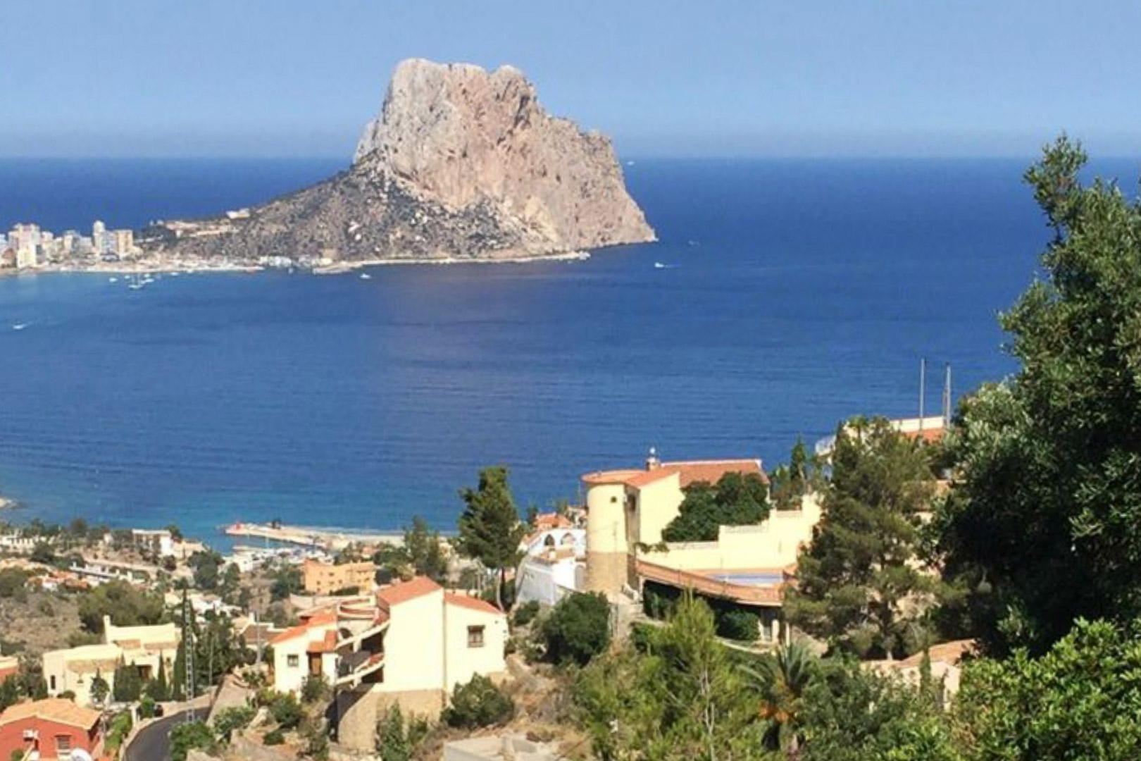 Verhoogd panoramisch uitzicht op de Peñón de Ifach en de Middellandse Zee, uitkijkend over het residentiële landschap en het groen van Calpe.