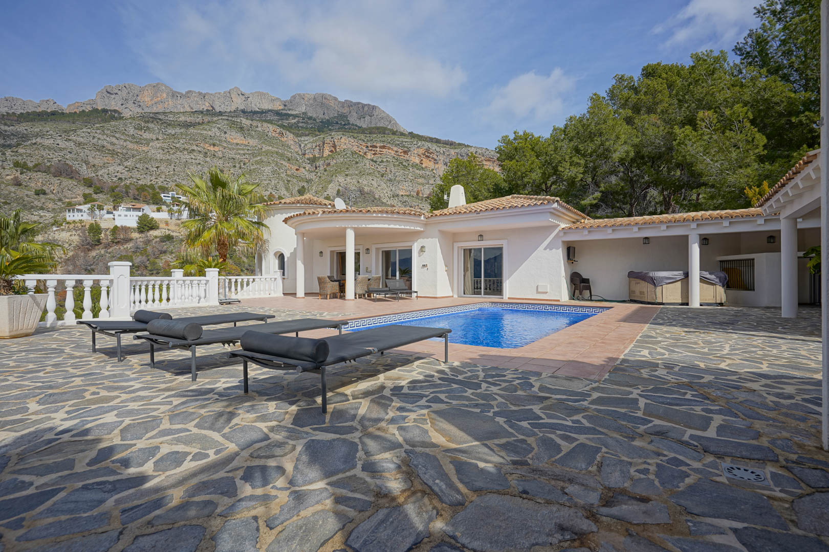 Hoofdterras met zwembad en natuurstenen bestrating, met panoramisch uitzicht op de Sierra de Bernia en de traditionele mediterrane architectuur van de villa.