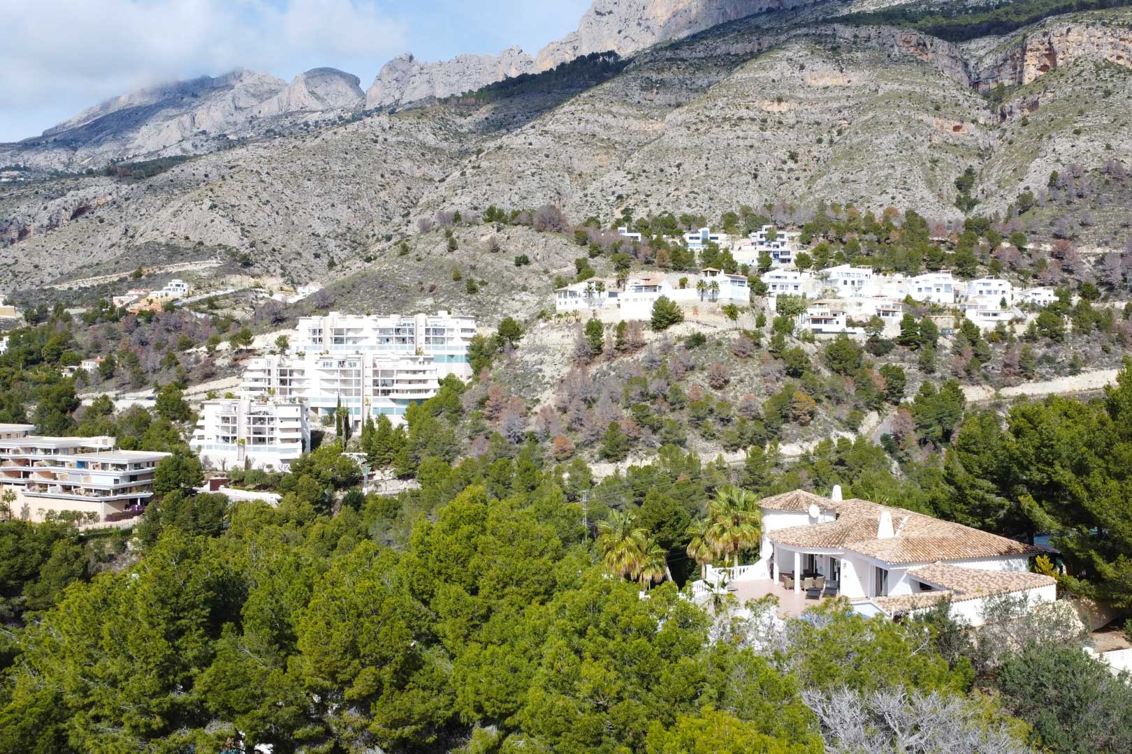 Luchtfoto van de mediterrane villa met pannendak, omgeven door pijnbomen aan de voet van het Sierra de Bernia gebergte in Altea.