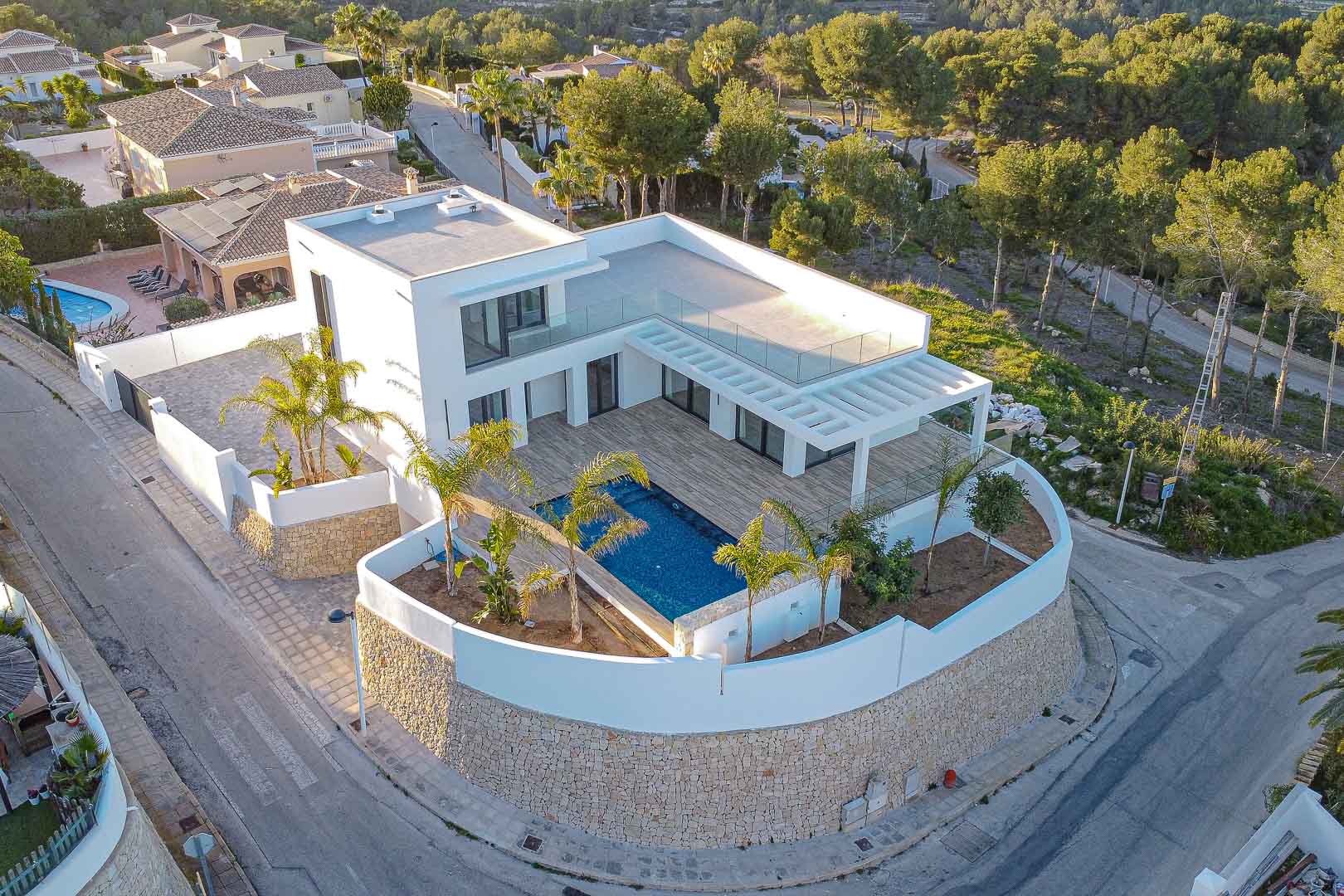 Luchtfoto van de moderne villa met blauw zwembad, terras met pergola en mediterrane tuin in Benimeit, Moraira.