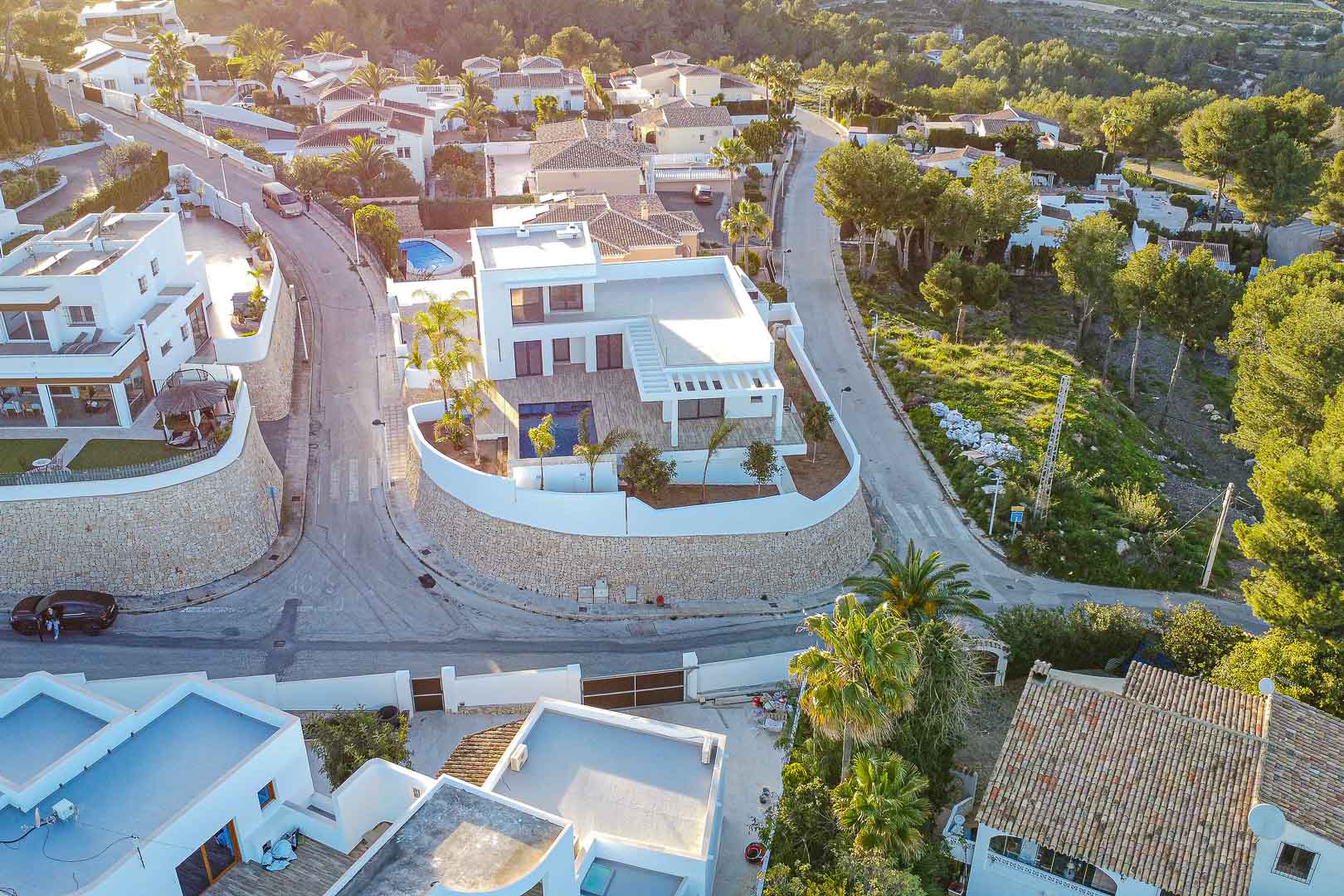Luchtfoto van een moderne villa met zwembad, omgeven door een stenen muur en tuinen in Benimeit, Moraira.