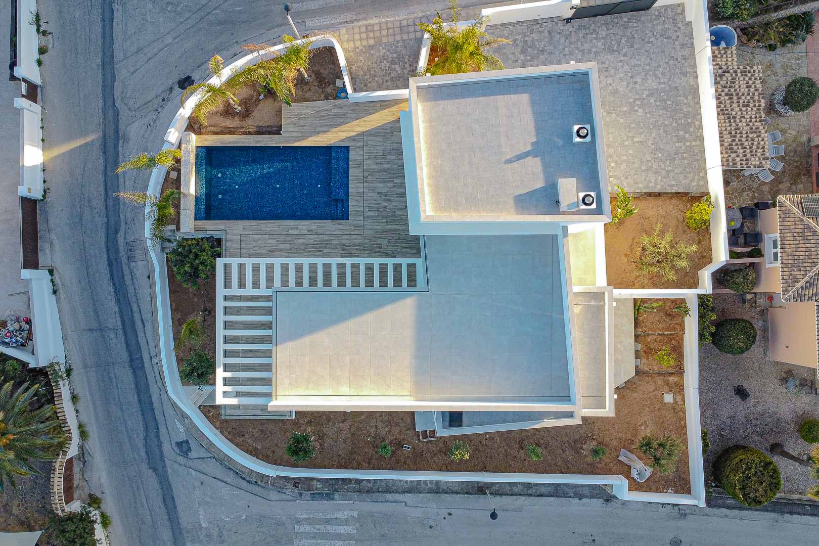 Luchtfoto van moderne villa in Benimeit met blauw zwembad en grijze betegelde terrassen.