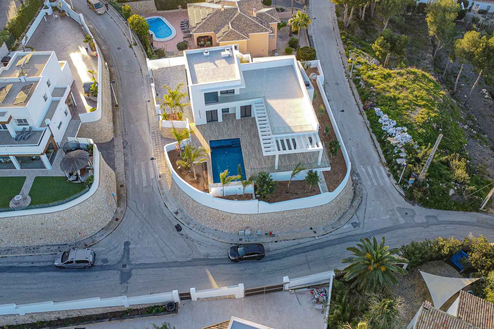 Luchtfoto van moderne villa met blauw zwembad, houten terrassen en mediterrane tuin in Benimeit, Moraira.