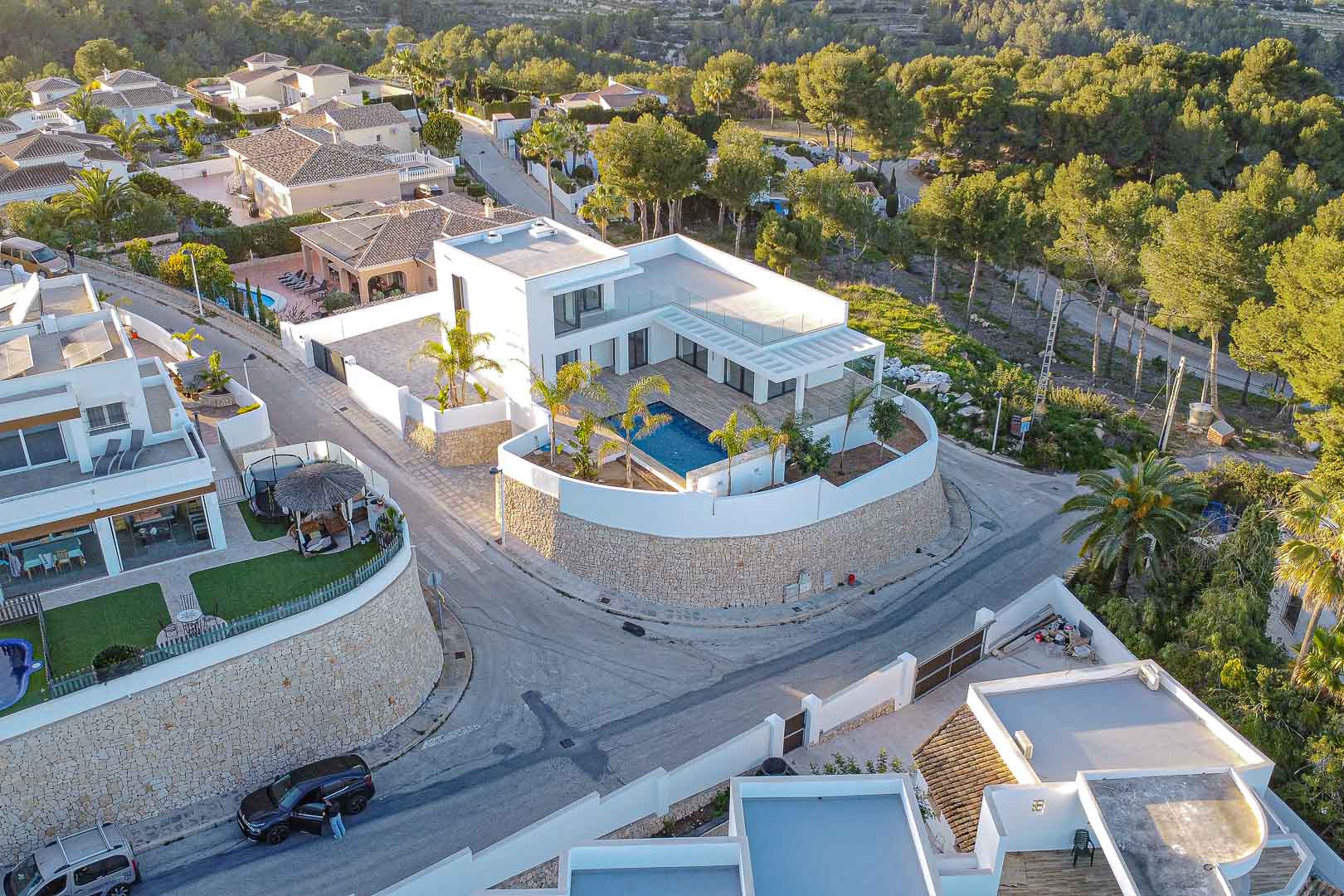 Luchtfoto van moderne villa met blauw zwembad, omgeven door stenen muur en groen in Benimeit, Moraira.