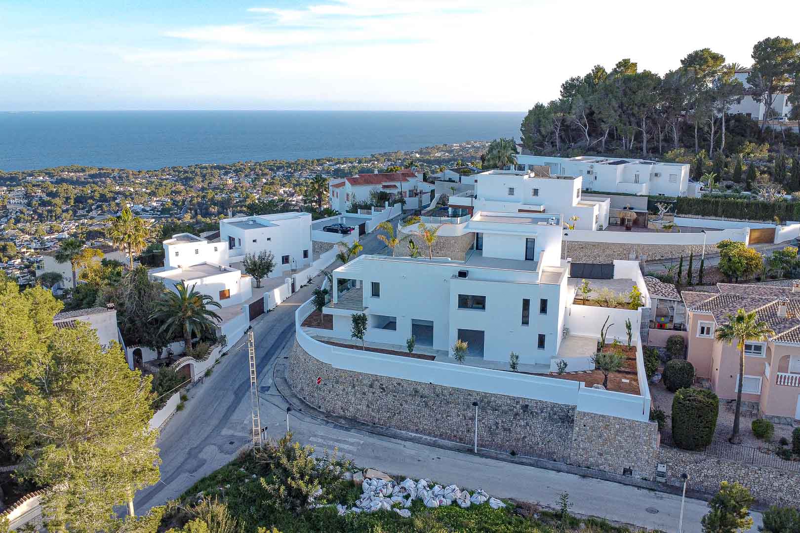 Luchtfoto van moderne witte villa met stenen muren en uitzicht op zee in Benimeit, Moraira.