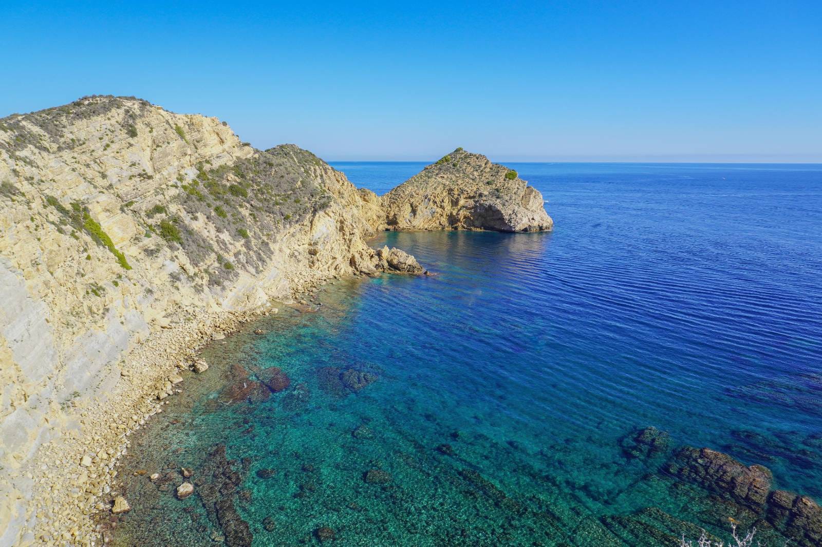 Panoramisch uitzicht op de kustlijn van Jávea met steile rotspartijen en kristalhelder turquoise water langs de Middellandse Zee.