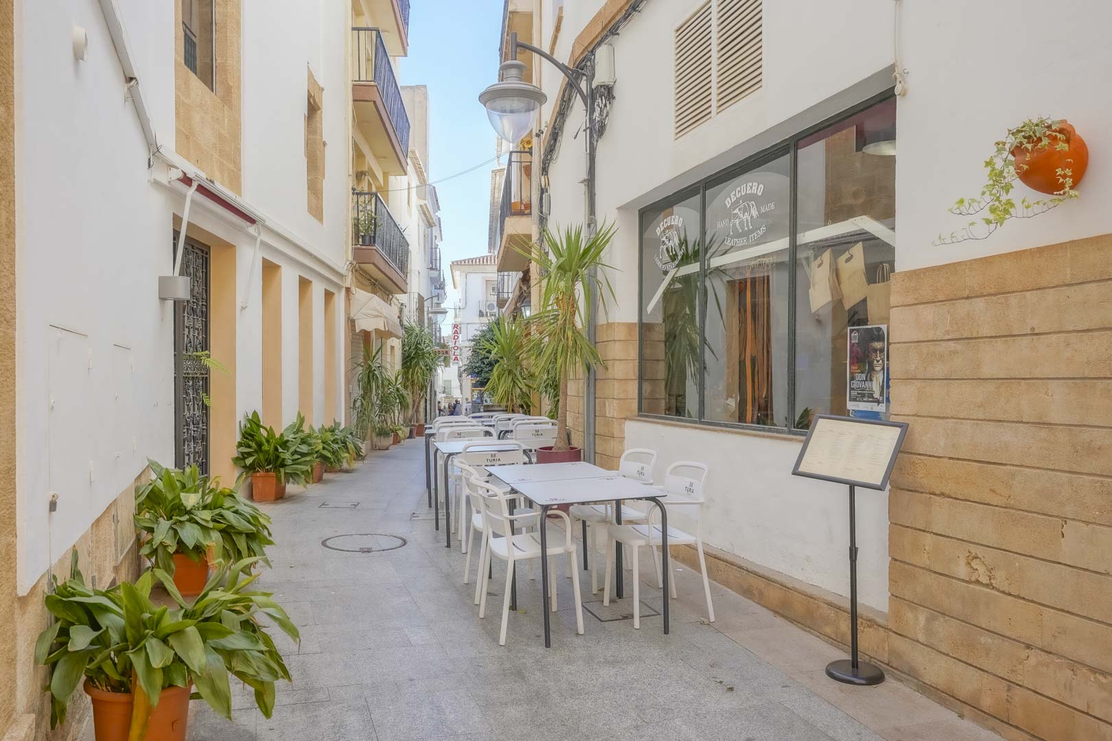 Traditionele voetgangersstraat in het historische centrum van Jávea, met Tosca stenen gevels, terrasjes en lokale ambachtelijke winkels.