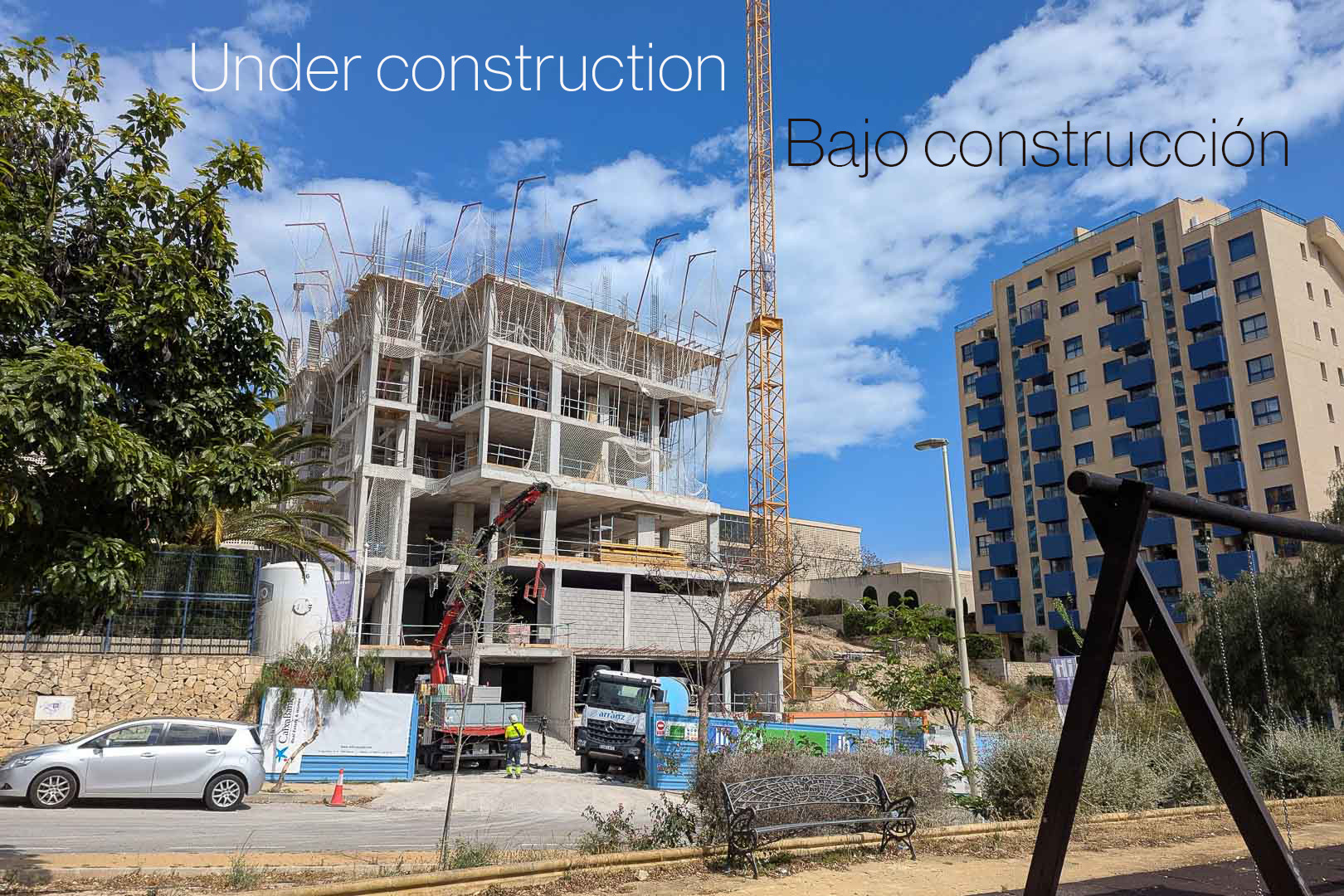 Exterieur van de eerste bouwfase in Calpe, met het betonnen skelet, de torenkraan en zware machines op de residentiële bouwplaats.