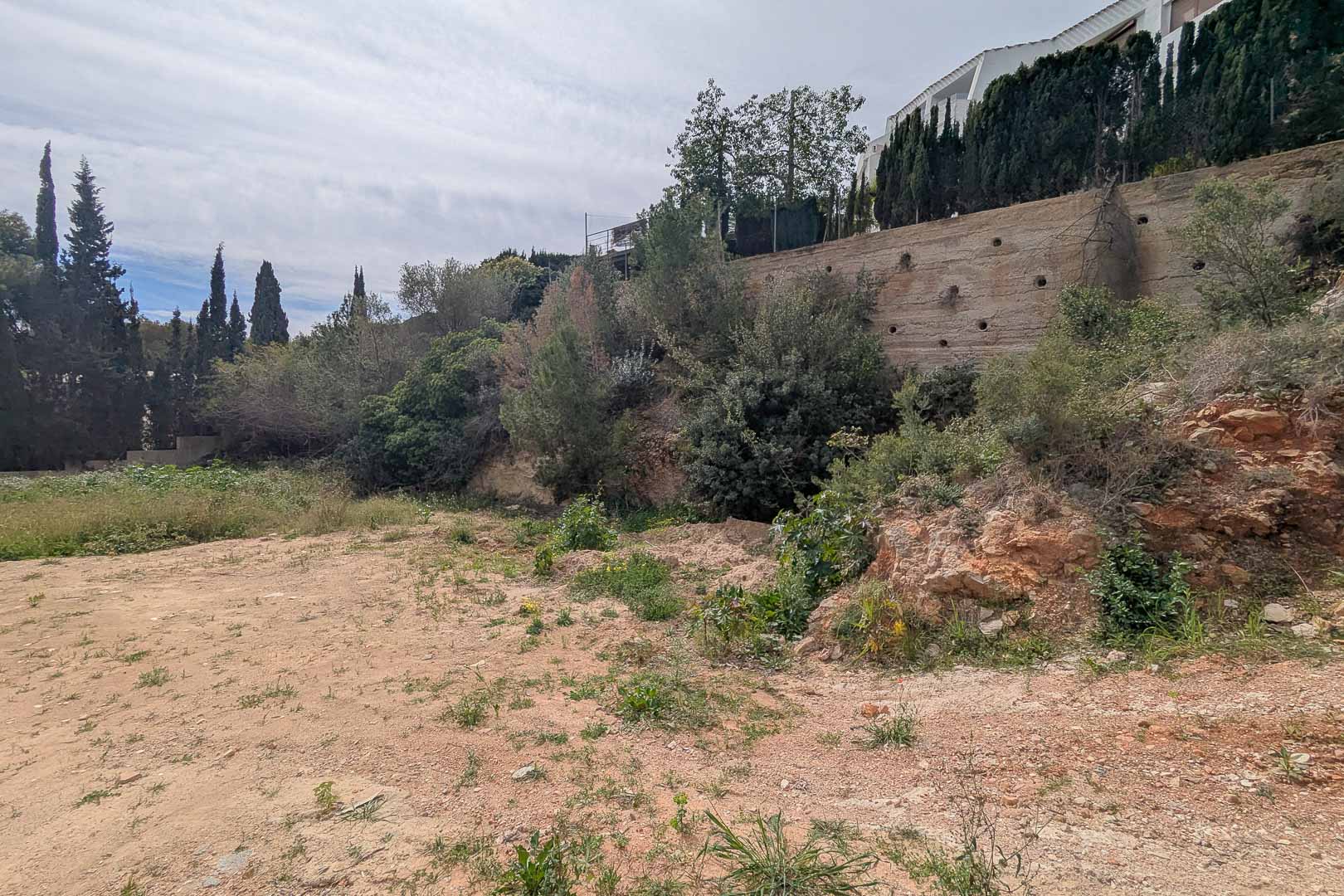 Verhoogd perceel in La Corona met een betonnen keurmuur en mediterrane beplanting. Het terrein is klaar voor de start van een op maat gemaakt villaproject.